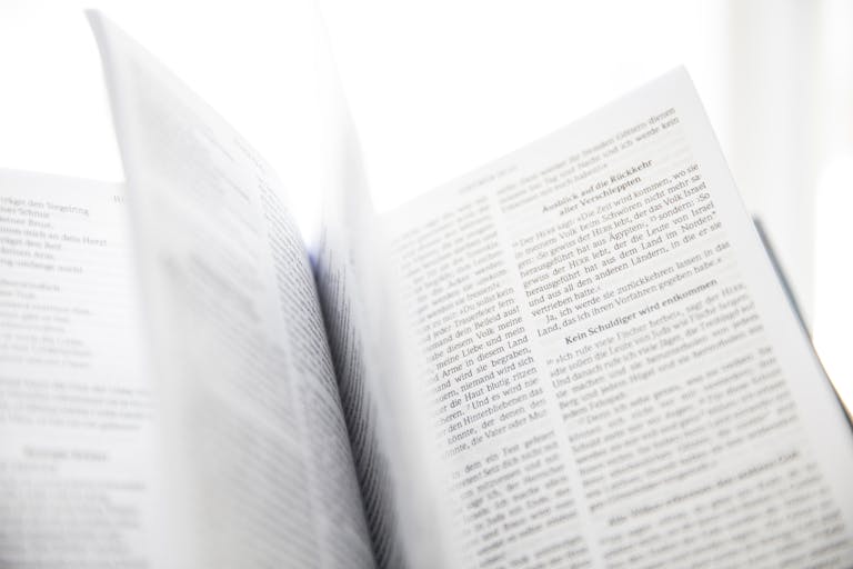 Close-up of an open book with visible text and turning pages in natural light.