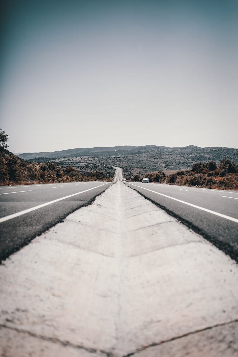Picturesque rural road with clear blue sky and distant mountains, conveying tranquility.