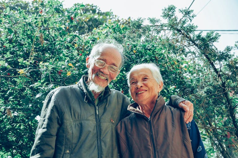 Senior couple enjoying a joyful moment together in a lush garden setting, exuding love and happiness.